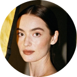Portrait of a woman with dark hair pulled back, wearing natural makeup and a neutral expression.