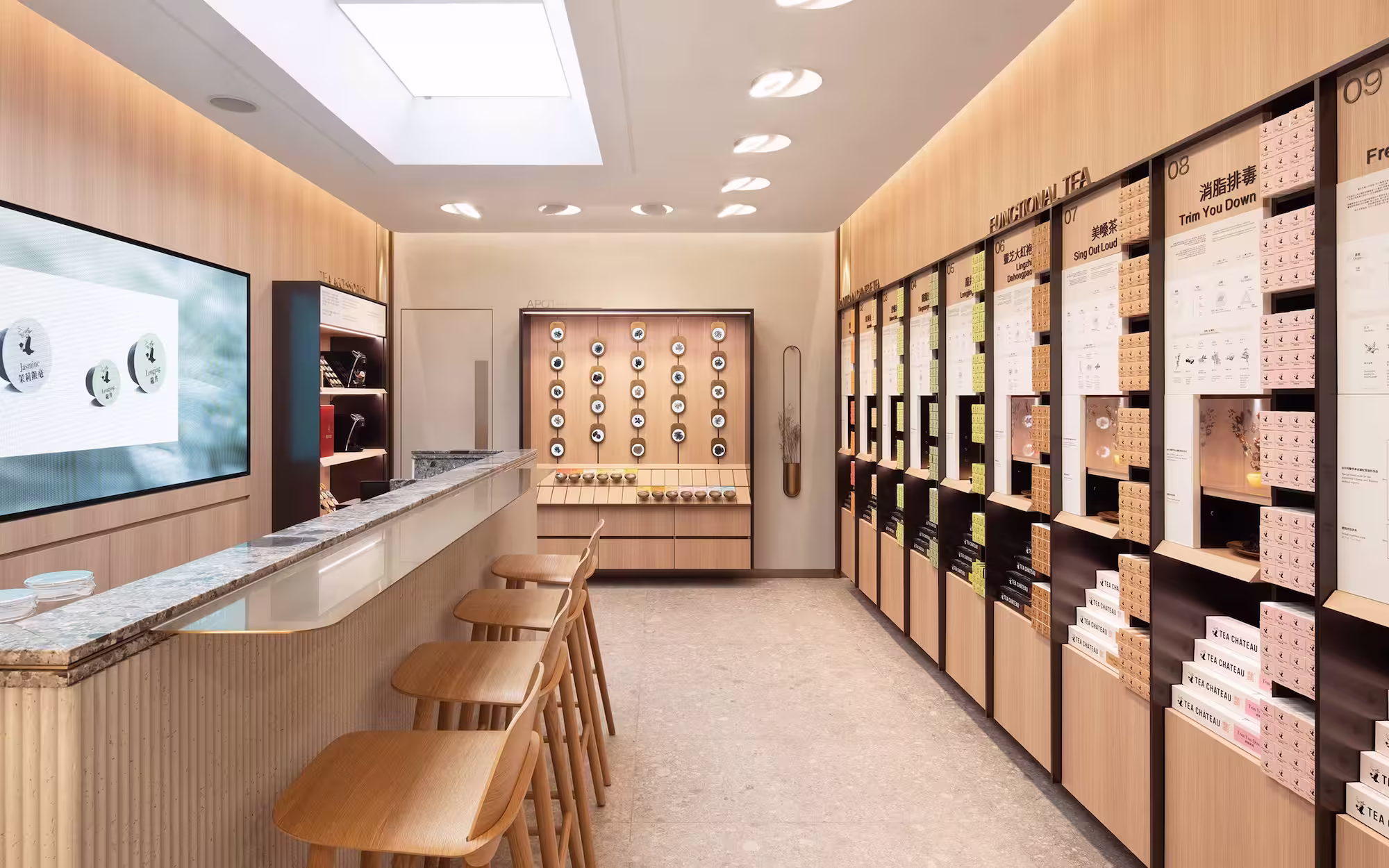 Modern tea shop interior with wooden bar stools, a marble counter, and shelves of functional teas.
